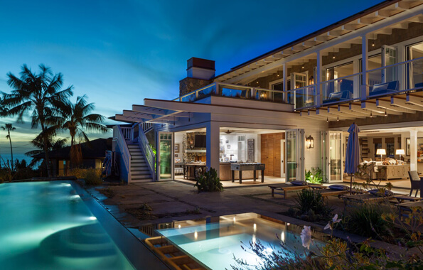 Backyard of big beach house with palm trees, pool, hot tubs, and lights