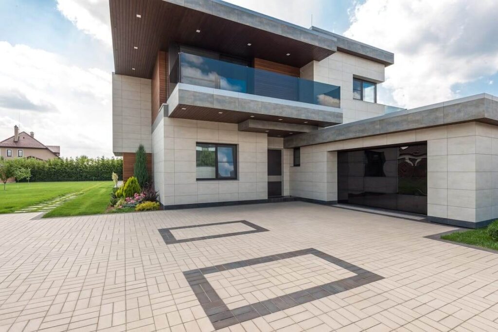 Two story house with glass garage, tiled driveway, and balcony on second floor