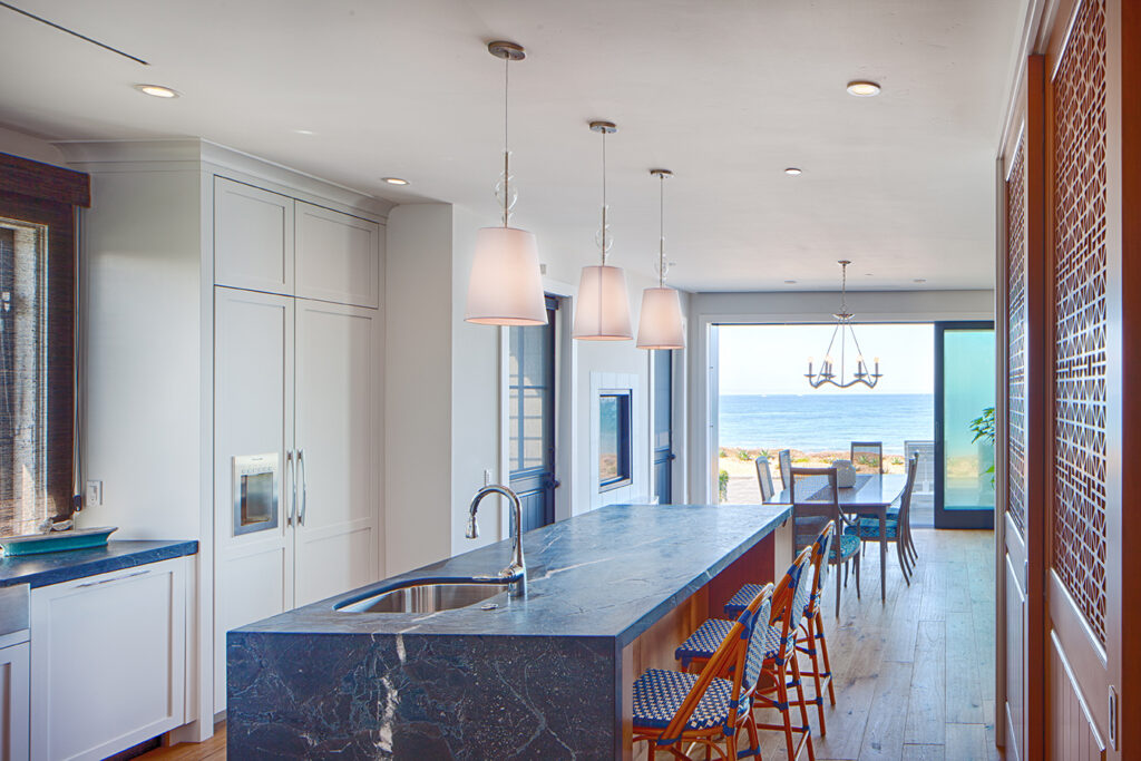 A minimalist kitchen featuring modern casement windows and multislide doors that allow natural light to reflect off premium surfaces.