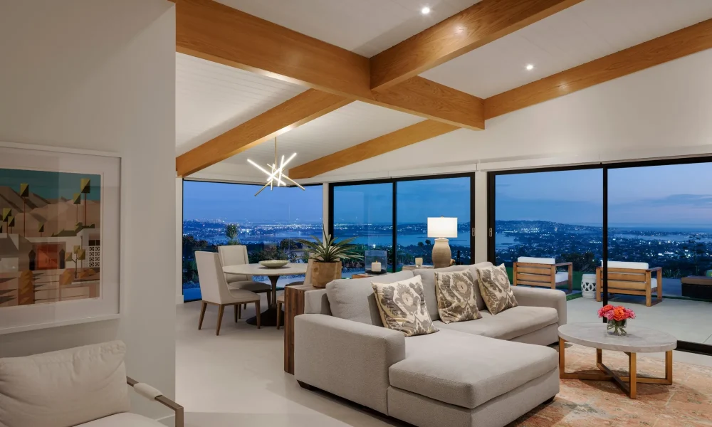 Living room with exposed wood beams and floor-to-ceiling sliding glass doors framing night views of Mission Bay
